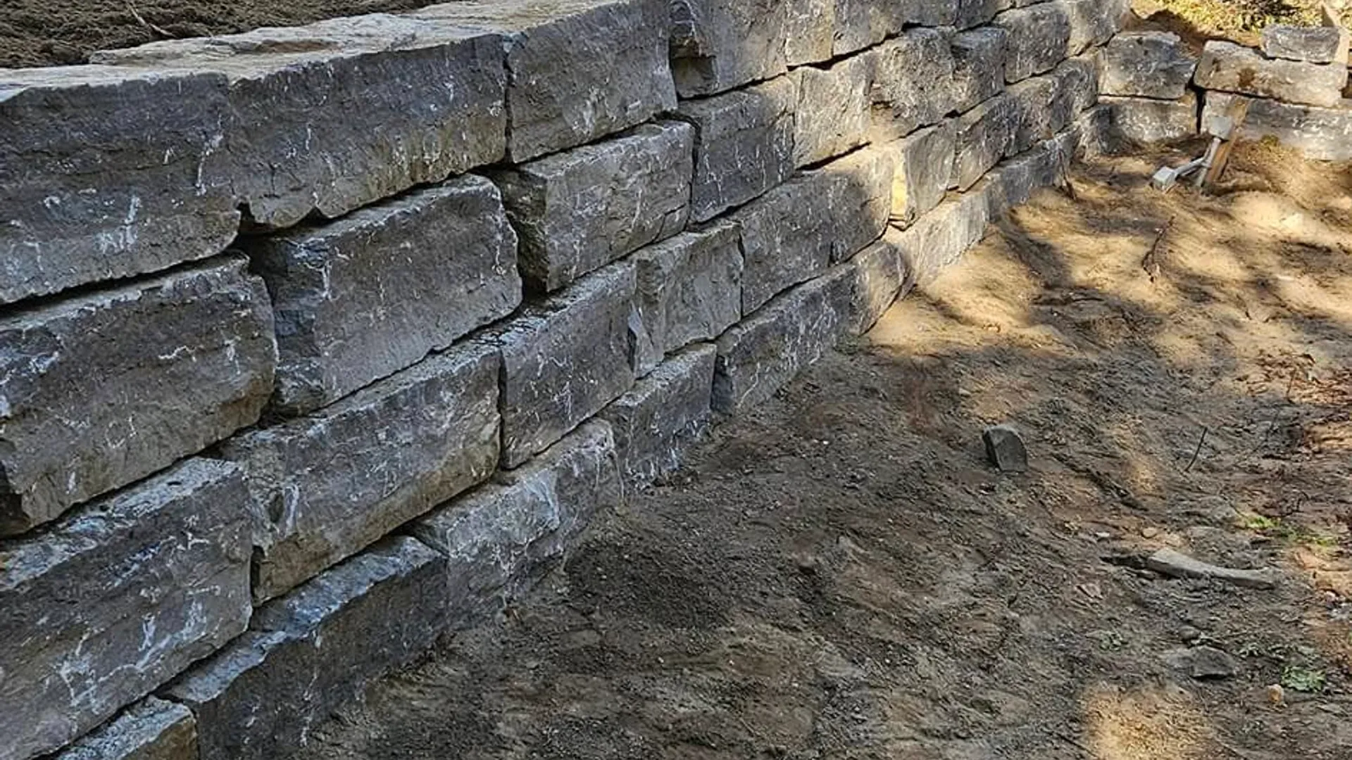 Muret de soutènement en pierre avec marches intégrées dans une cour