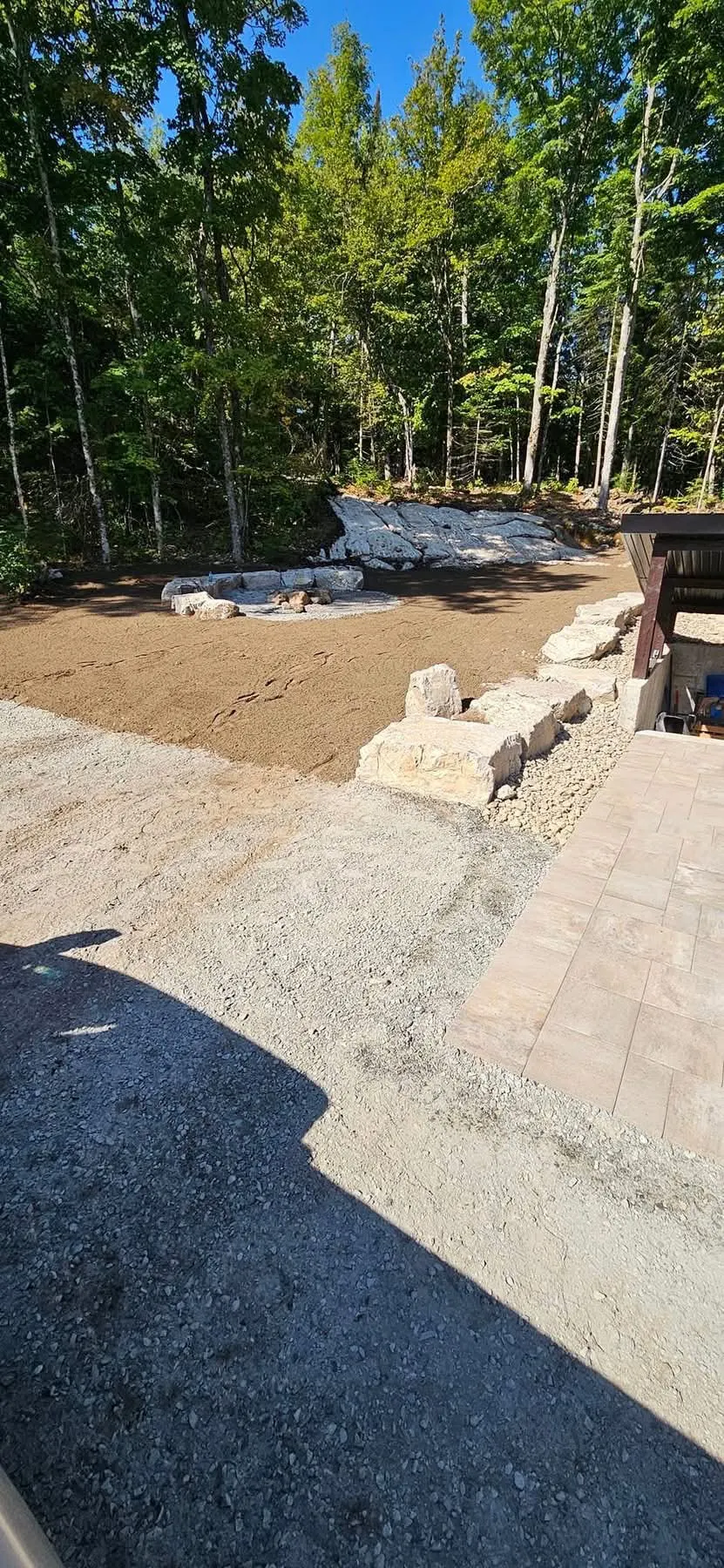 Terrassement et aménagement d’une cour boisée avec muret de pierre
